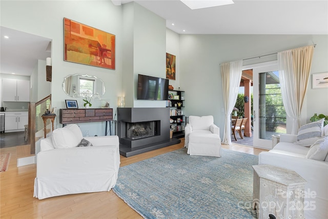 living area with healthy amount of natural light, high vaulted ceiling, light wood-type flooring, a multi sided fireplace, and recessed lighting