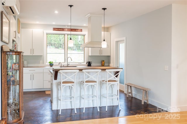 kitchen with a wall mounted AC, hanging light fixtures, white cabinetry, a kitchen breakfast bar, and recessed lighting