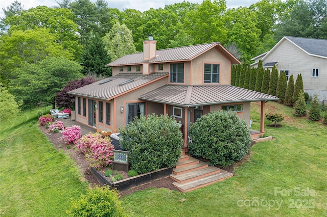 back of property featuring a standing seam roof, metal roof, a chimney, and stucco siding