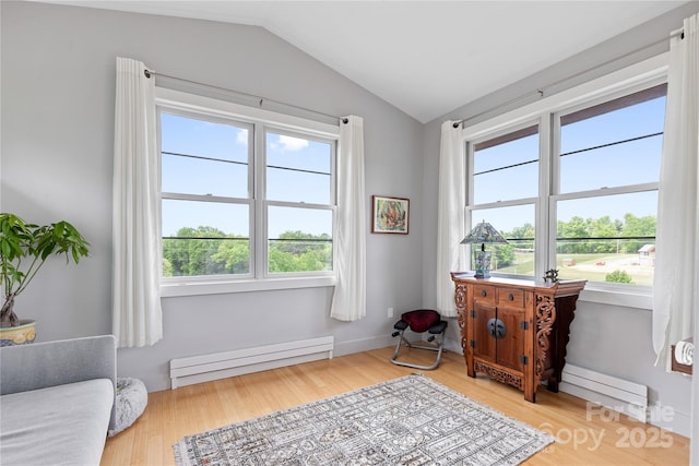 sitting room featuring a baseboard heating unit, plenty of natural light, lofted ceiling, and light wood-type flooring