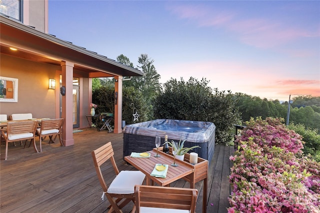 deck at dusk with outdoor dining area and a hot tub