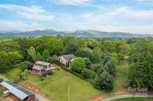 aerial view of property and surrounding area featuring a mountainous background and a forest