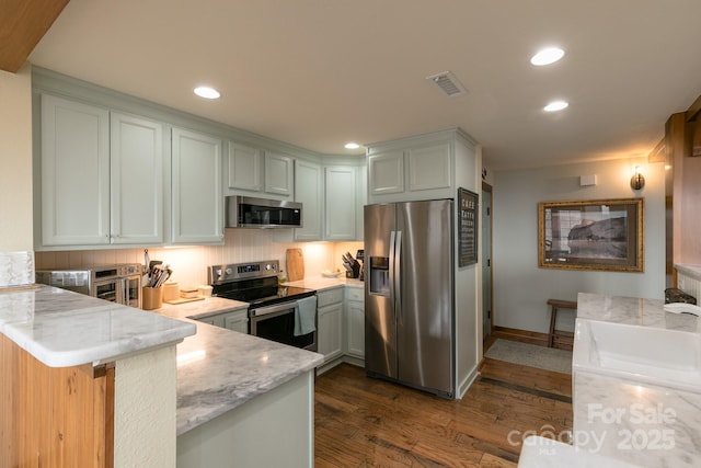 61 Creekside Way Unit G/101, Burnsville, NC 28714 - kitchen featuring appliances with stainless steel finishes, a peninsula, dark wood-style floors, recessed lighting, and light stone counters