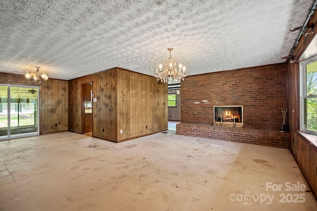 1 Ola Dr, Candler, NC 28715 - unfurnished living room with a chandelier, a brick fireplace, wood walls, and concrete flooring