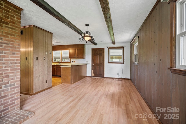 1 Ola Dr, Candler, NC 28715 - kitchen featuring light wood-style flooring, brown cabinetry, a peninsula, beamed ceiling, and light countertops