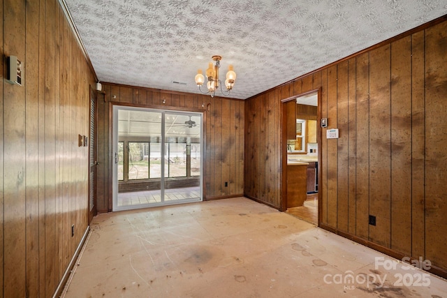 1 Ola Dr, Candler, NC 28715 - spare room featuring a chandelier, wood walls, baseboards, and a textured ceiling