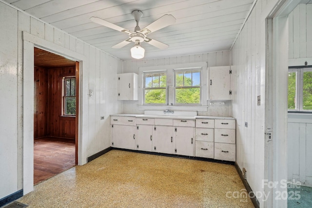 1 Ola Dr, Candler, NC 28715 - kitchen featuring light countertops, white cabinetry, healthy amount of natural light, a sink, and wood walls