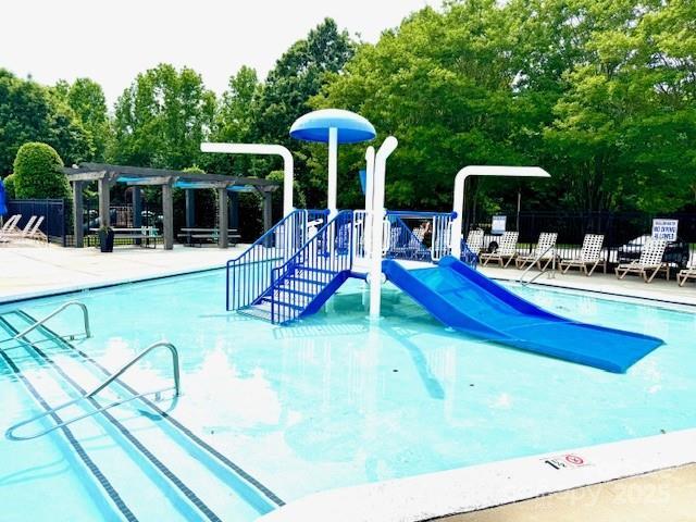 10008 King George Ln, Waxhaw, NC 28173 - community pool featuring a water play area, a pergola, fence, and view of wooded area