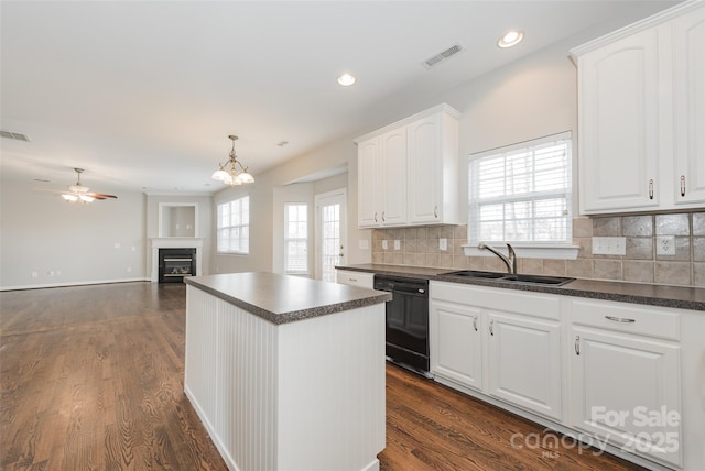 10008 King George Ln, Waxhaw, NC 28173 - kitchen with a sink, dark countertops, black dishwasher, a center island, and a glass covered fireplace
