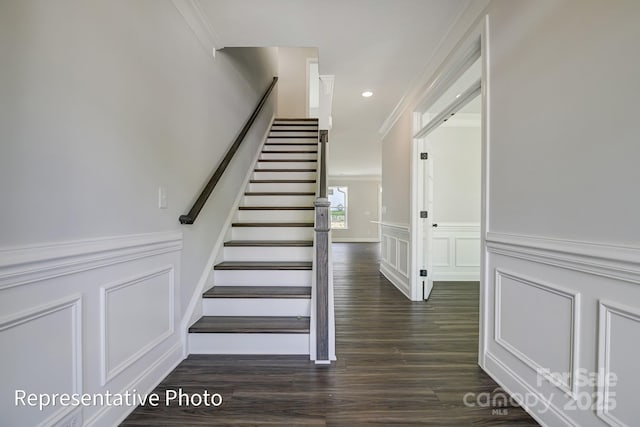 stairway with a decorative wall, ornamental molding, wood finished floors, wainscoting, and recessed lighting