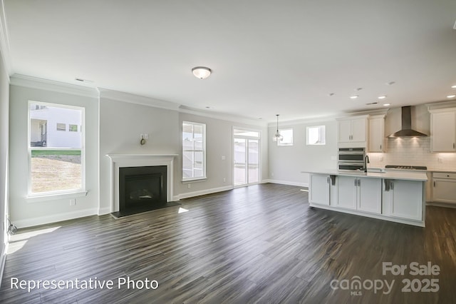 kitchen featuring wall chimney exhaust hood, ornamental molding, light countertops, a fireplace, and dark wood-style floors