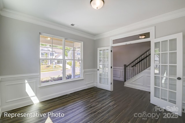 foyer featuring french doors, dark wood-type flooring, stairs, ornamental molding, and a wainscoted wall