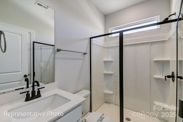 bathroom featuring a shower stall, toilet, and vanity