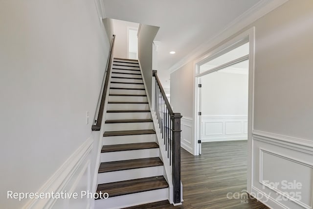 stairs featuring crown molding, a decorative wall, wood finished floors, and wainscoting