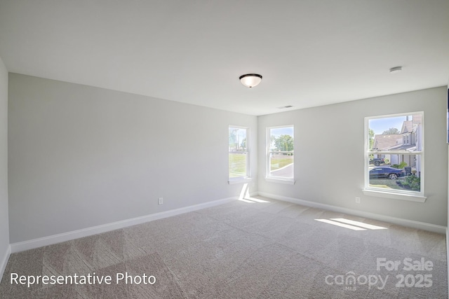 carpeted spare room with baseboards, plenty of natural light, and a smoke detector