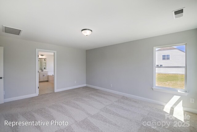 unfurnished bedroom featuring light carpet, baseboards, and connected bathroom
