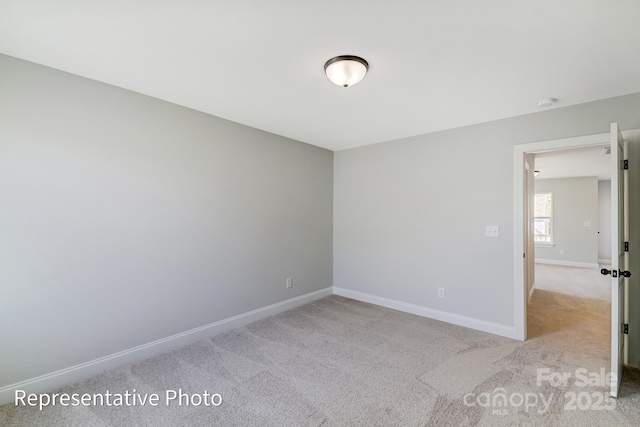 empty room featuring carpet floors, baseboards, and a smoke detector