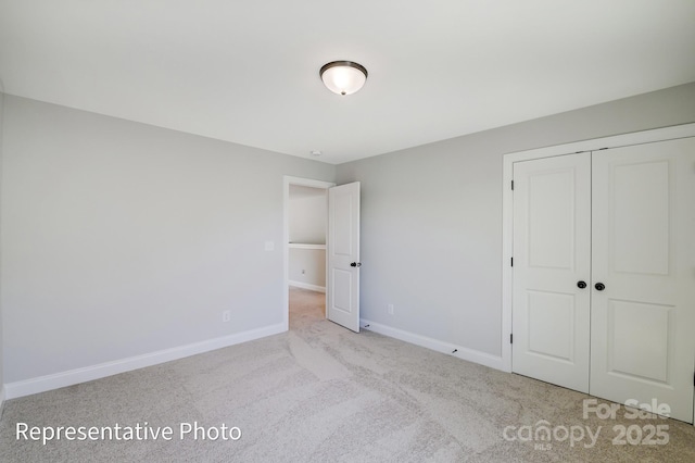 unfurnished bedroom with baseboards, carpet flooring, and a closet