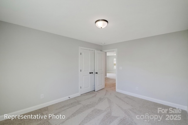 unfurnished room with baseboards and light colored carpet
