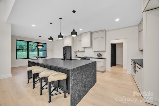1141 Harper Lee Dr, Newton, NC 28658 - kitchen with dark countertops, light wood finished floors, a breakfast bar, an island with sink, and recessed lighting