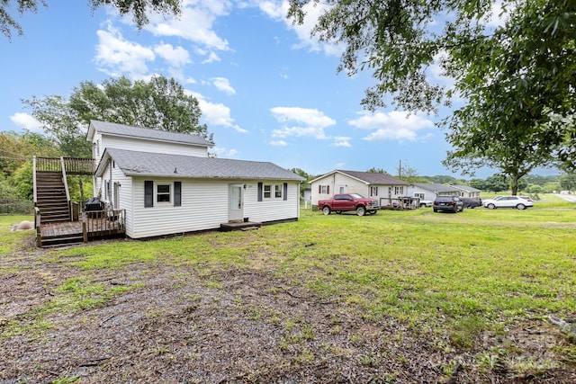 rear view of property featuring a yard, a deck, roof with shingles, and stairway