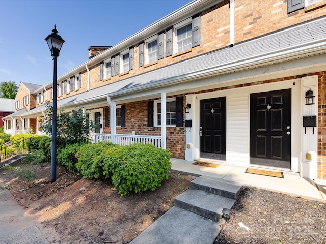 view of front of house featuring brick siding and a porch
