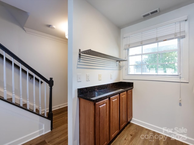 bar with wood finished floors, stairs, baseboards, and crown molding