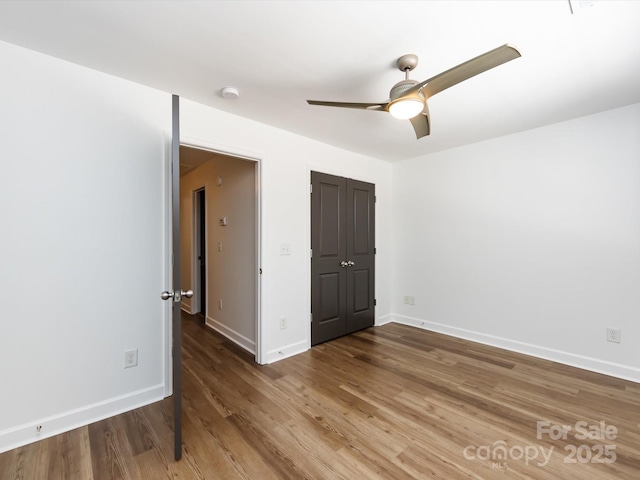 unfurnished bedroom with wood finished floors, baseboards, a ceiling fan, and a closet
