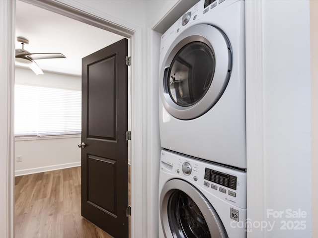 laundry area featuring stacked washer and clothes dryer, light wood-type flooring, baseboards, and ceiling fan
