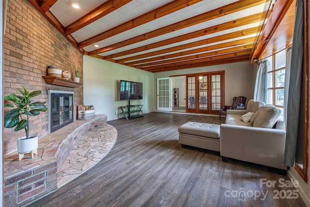 living area featuring wood finished floors, a fireplace, french doors, and beam ceiling