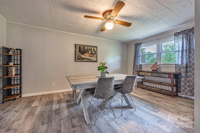 dining area featuring crown molding, wood finished floors, a ceiling fan, and baseboards