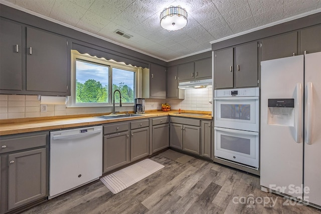 kitchen with white appliances, a sink, wooden counters, backsplash, and gray cabinets