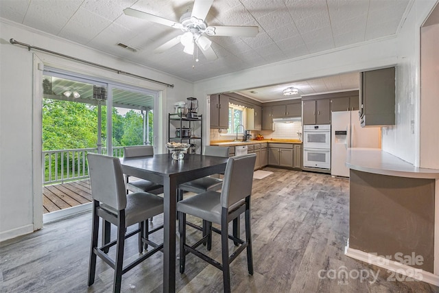 dining area featuring crown molding, light wood-style flooring, and ceiling fan