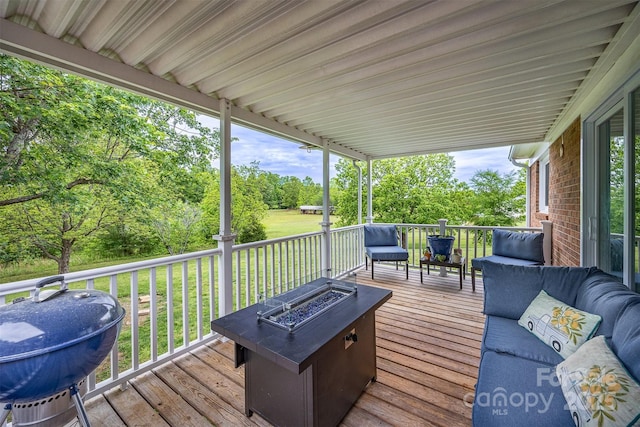 wooden deck featuring view of wooded area, a lawn, and an outdoor living space with a fire pit