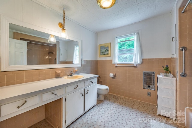 bathroom with heating unit, tile walls, a shower, vanity, and toilet
