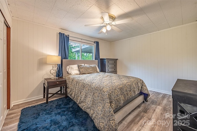 bedroom featuring wood finished floors, baseboards, ceiling fan, and ornamental molding
