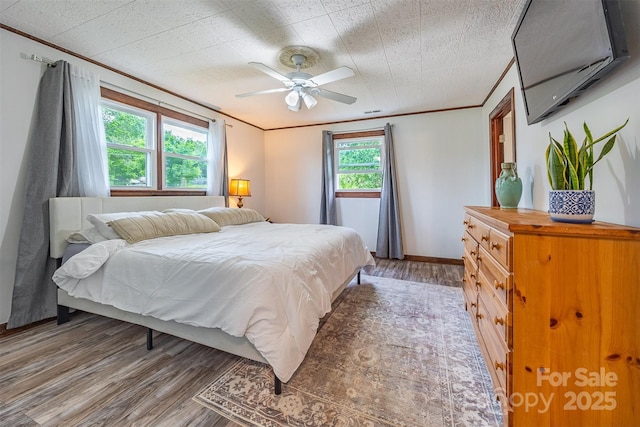 bedroom with light wood-type flooring, crown molding, and ceiling fan
