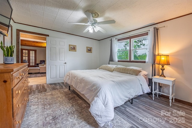 bedroom with wood finished floors, crown molding, ceiling fan, and baseboards