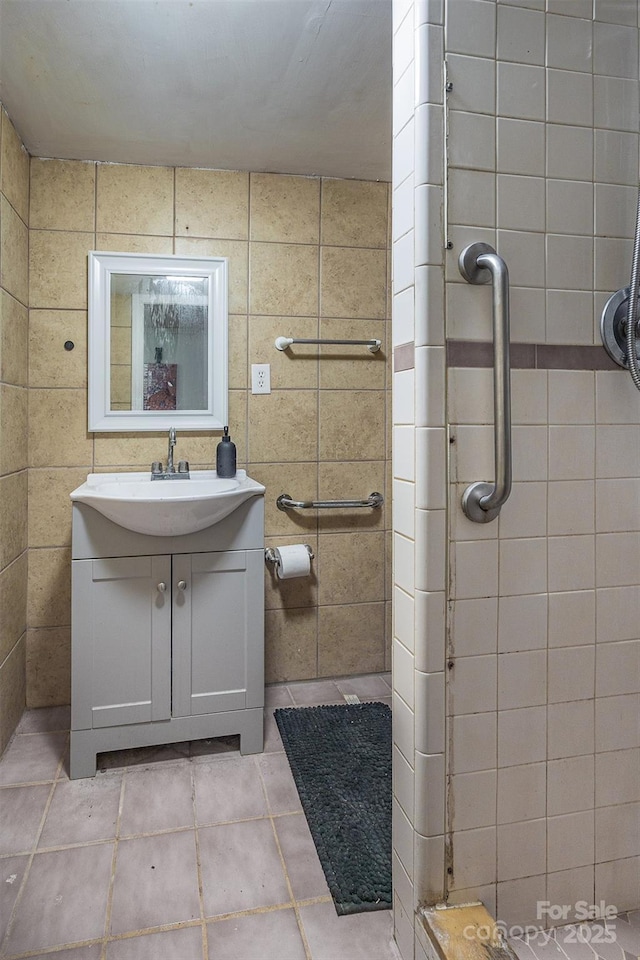 bathroom featuring a tile shower, vanity, and tile patterned flooring