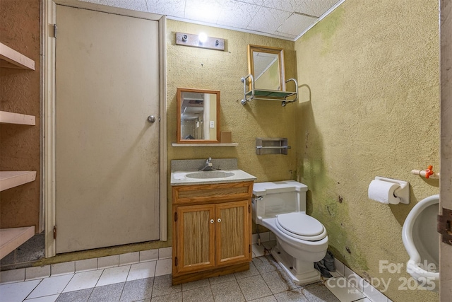 half bath with toilet, vanity, and tile patterned floors