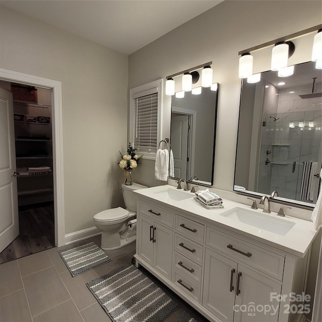 5118 Regents Park Dr, Hickory, NC 28602 - full bathroom featuring a stall shower, double vanity, toilet, a walk in closet, and baseboards