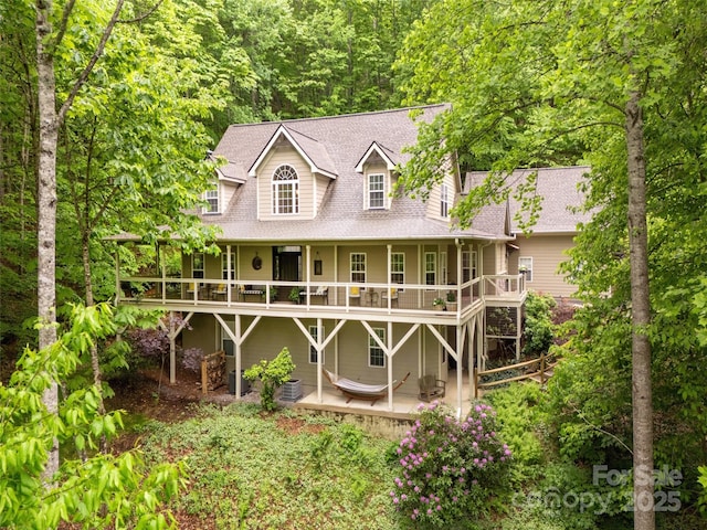 rear view of house featuring roof with shingles, a patio, and a wooden deck