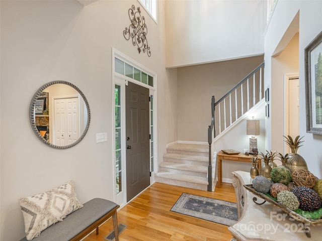 entrance foyer featuring stairs, wood finished floors, and a high ceiling