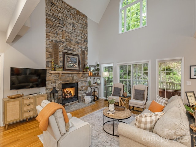 living area featuring light wood-style flooring, a fireplace, and high vaulted ceiling