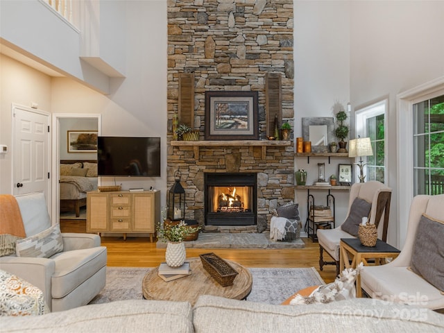 living area with a fireplace, wood finished floors, and a towering ceiling