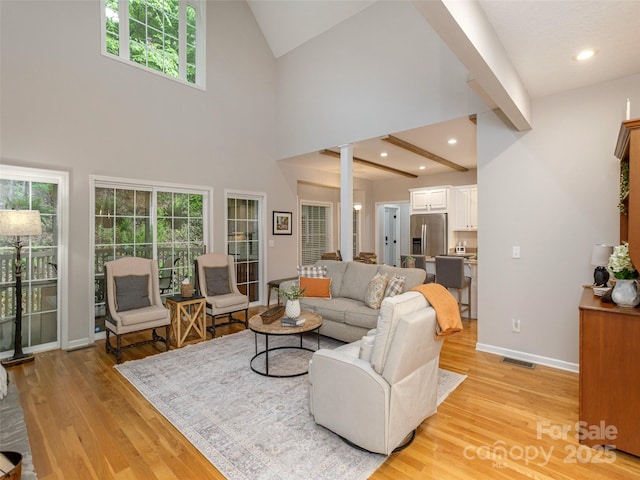 living room featuring healthy amount of natural light, light wood-type flooring, baseboards, high vaulted ceiling, and recessed lighting