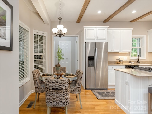 kitchen featuring stainless steel fridge, beamed ceiling, light wood finished floors, white cabinets, and hanging light fixtures