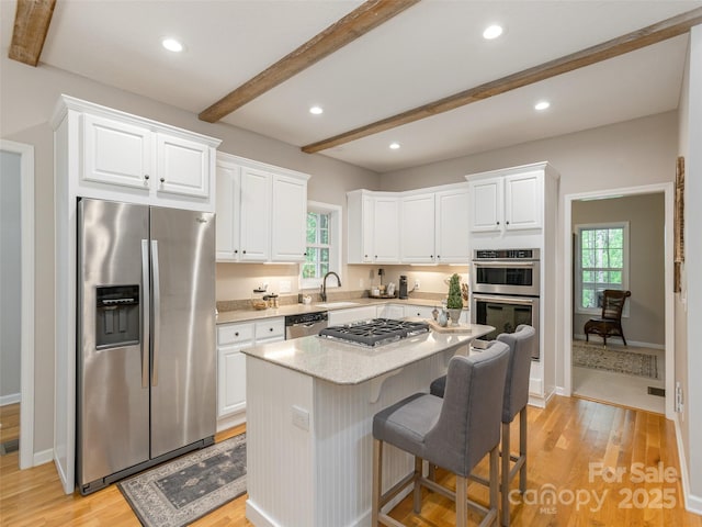 kitchen featuring appliances with stainless steel finishes, beamed ceiling, white cabinets, light wood-style flooring, and recessed lighting