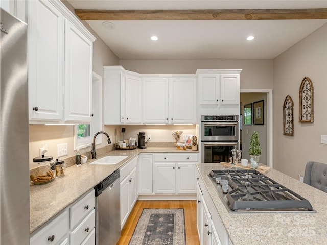kitchen with a sink, appliances with stainless steel finishes, light wood finished floors, white cabinetry, and recessed lighting