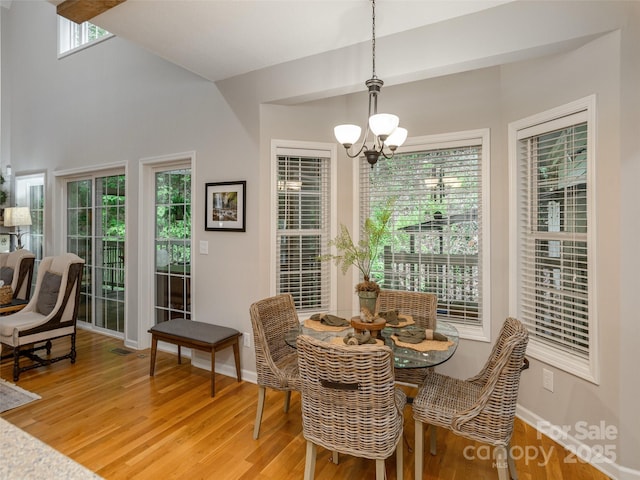 dining room with a chandelier, light wood-style flooring, baseboards, and a towering ceiling